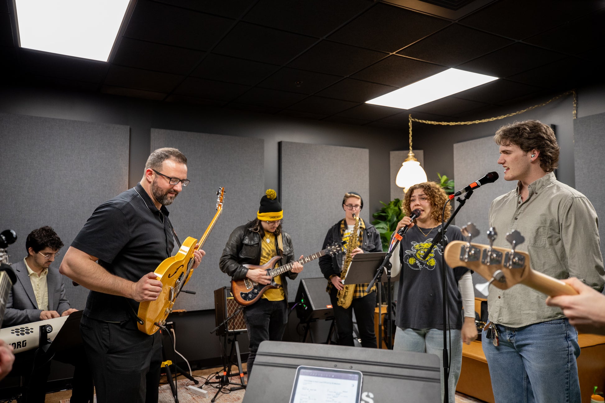 Band playing music in a room with musical instruments and equipment.